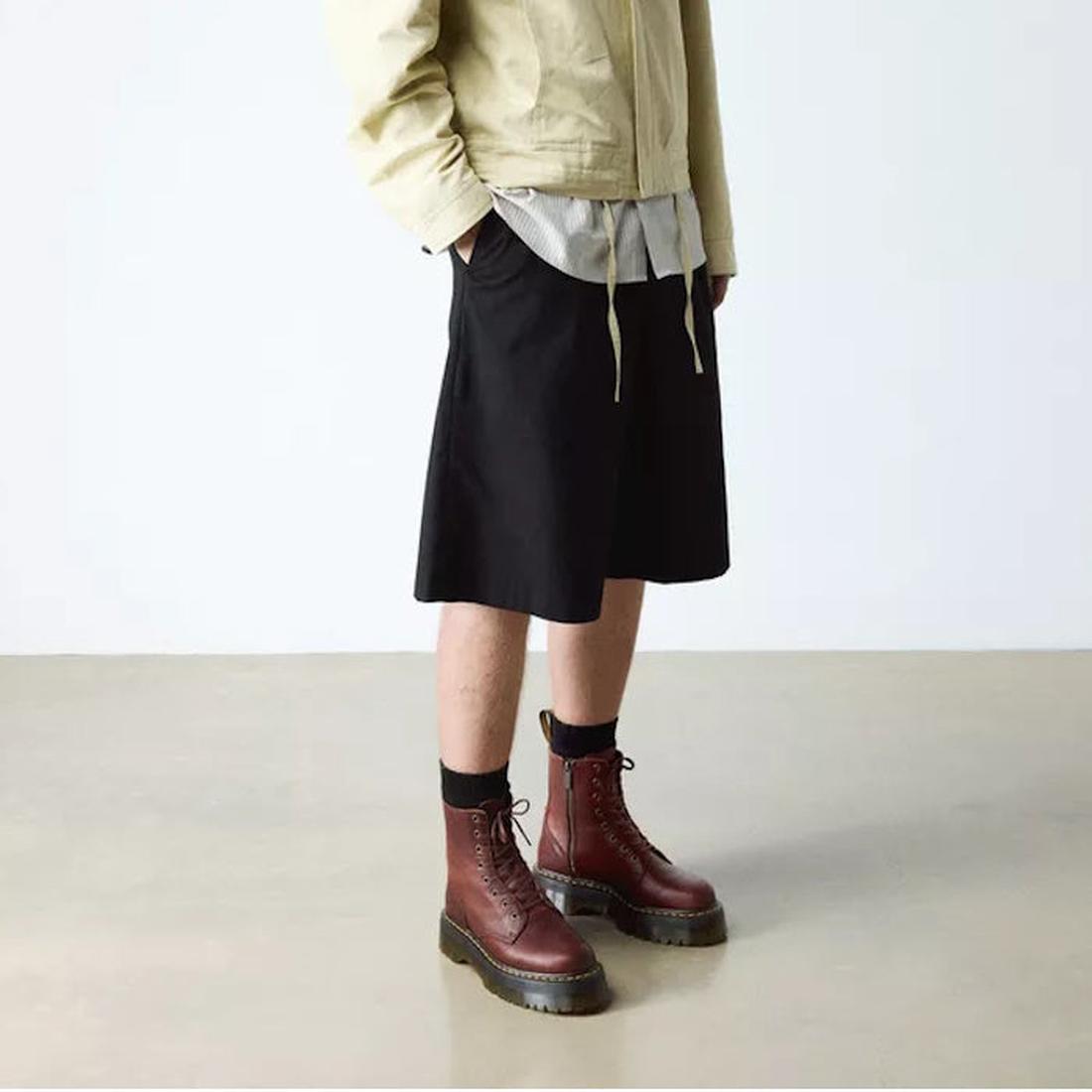Person standing indoors wearing a tan jacket, striped shirt, black knee-length shorts, black socks, and Dr Martens Jadon Cashew Tan Ambassador Leather Zip Boots with platform soles. The person’s face is not visible in the image., 190665749038, 19066574904