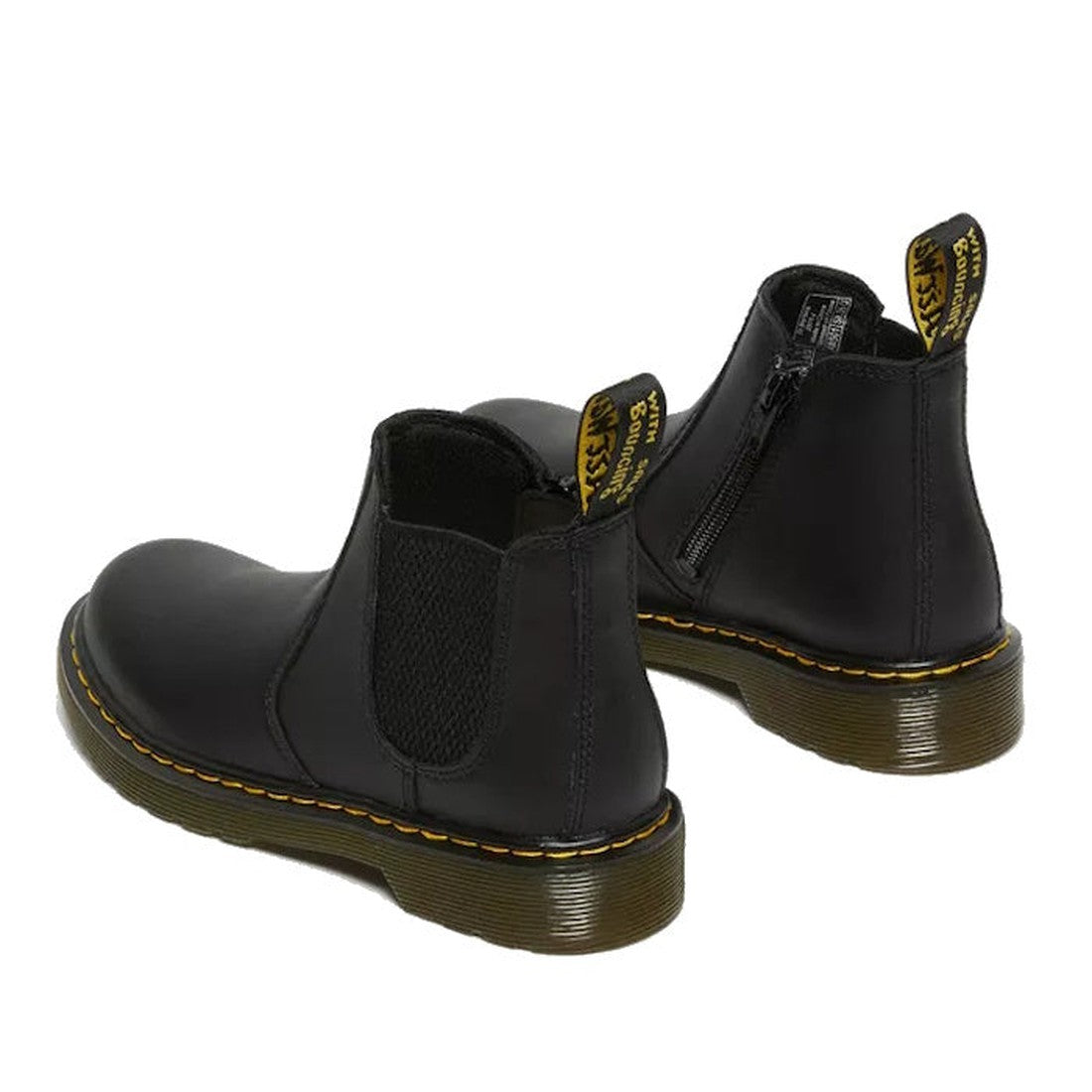 The Dr Martens kids 2976 Juniors Chelsea School Boot in black leather features elastic side panels, a side zipper, back pull tabs with yellow branding, and yellow stitching; shown from the back and side on a white background., 883985847491, 883985847507, 