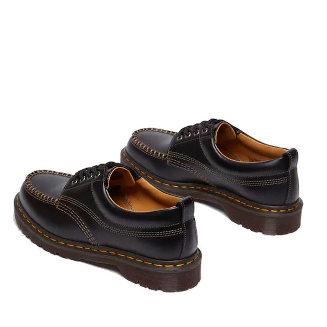 The Dr Martens Lowell Moc Toe Black Leather Shoe features black Analine leather, brown stitching, thick soles, and yellow Goodyear welted details, shown from a rear side angle on a white background., 50395, 50396, 50397, 50398, 50399, 190665668940, 190665