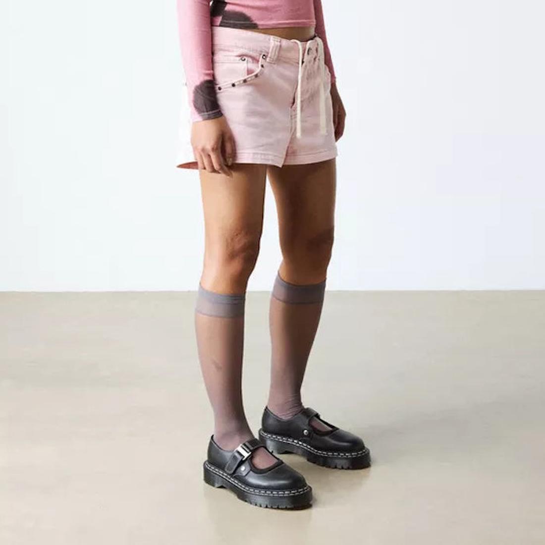A person in a bright outfit shows off comfy Dr Martens Mary Jane WDS Bex shoes—black leather, white stitching, sturdy sole, buckle closure.  ksnz, 190665785807, 190665785814, 190665785821, 190665785845, 190665785869