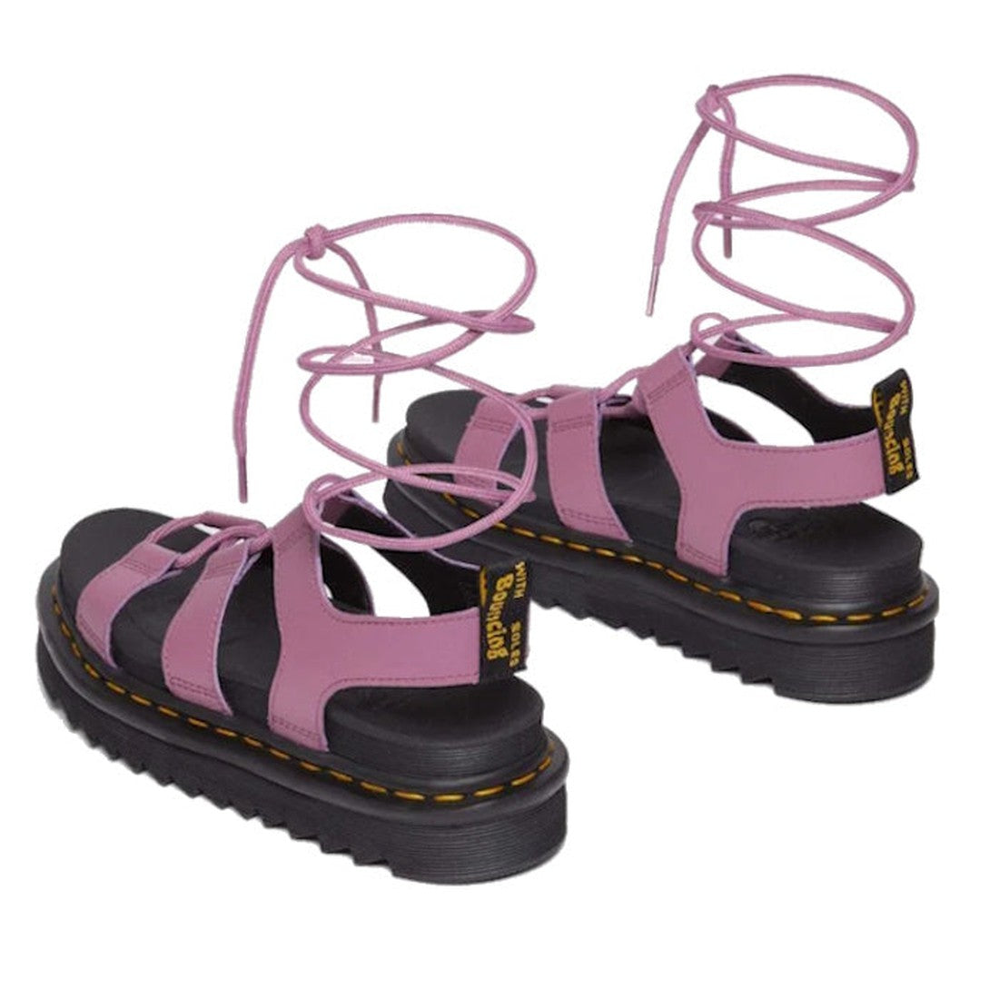 The Dr Martens Nartilla Gladiator Sandal Mauve Pink Athena Clearance features pink leather, thick black Goodyear welted soles, yellow stitching, ankle lace-up straps, and a Dr. Martens logo tag on the heel.