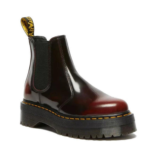 The Dr Martens 2976 Quad Cherry Red Arcadia Leather Chelsea Boot features a shiny dark cherry-red leather, thick black platform sole, yellow stitching, black elastic side panels, and a yellow pull tab at the back.