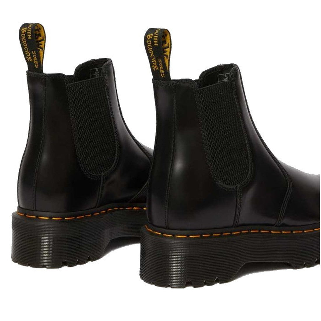 The Dr Martens - 2976 Quad Chelsea Black Boot features black leather, an air-cushioned sole, side elastic panels, yellow stitching, and pull tabs with yellow text. Boots are angled to display the side and back., 190665239621, 190665239638, 190665239645, 1