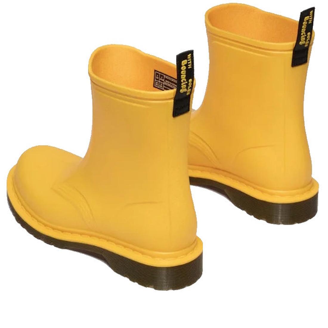 A pair of Dr Martens 1460 Sub Max Pull On Rain Boot Yellow PVC with black pull tabs and thick dark brown soles, styled with one boot forward and one angled—ideal as a stylish waterproof choice for wet days., 49435, 190665746464, 190665746471, 190665746495