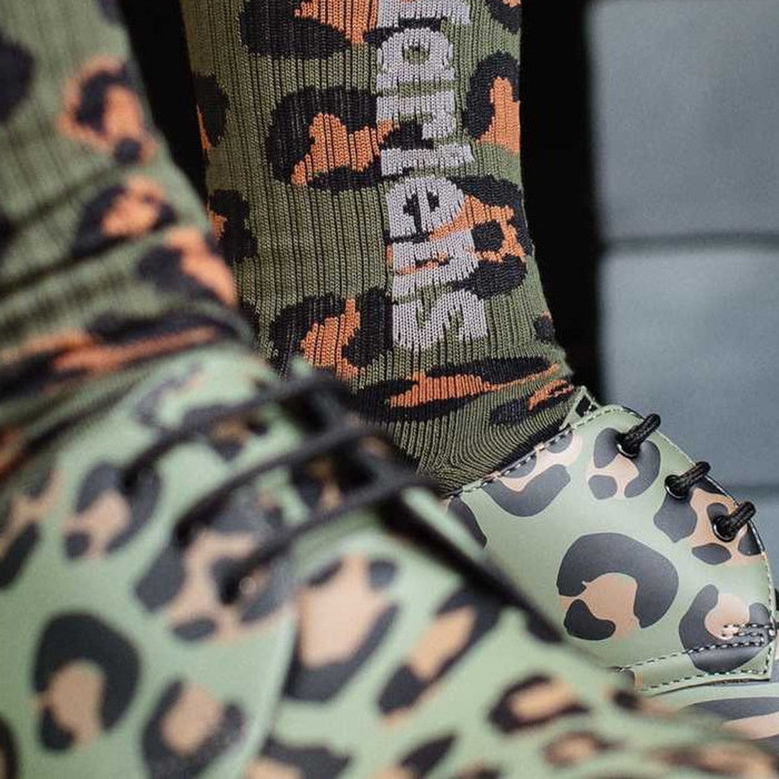 Dr Martens Green Ankle Boots with sturdy sole and lace-up front, paired with cozy cotton socks in a khaki camo leopard print.  ksnz, 190665515374, 190665515367