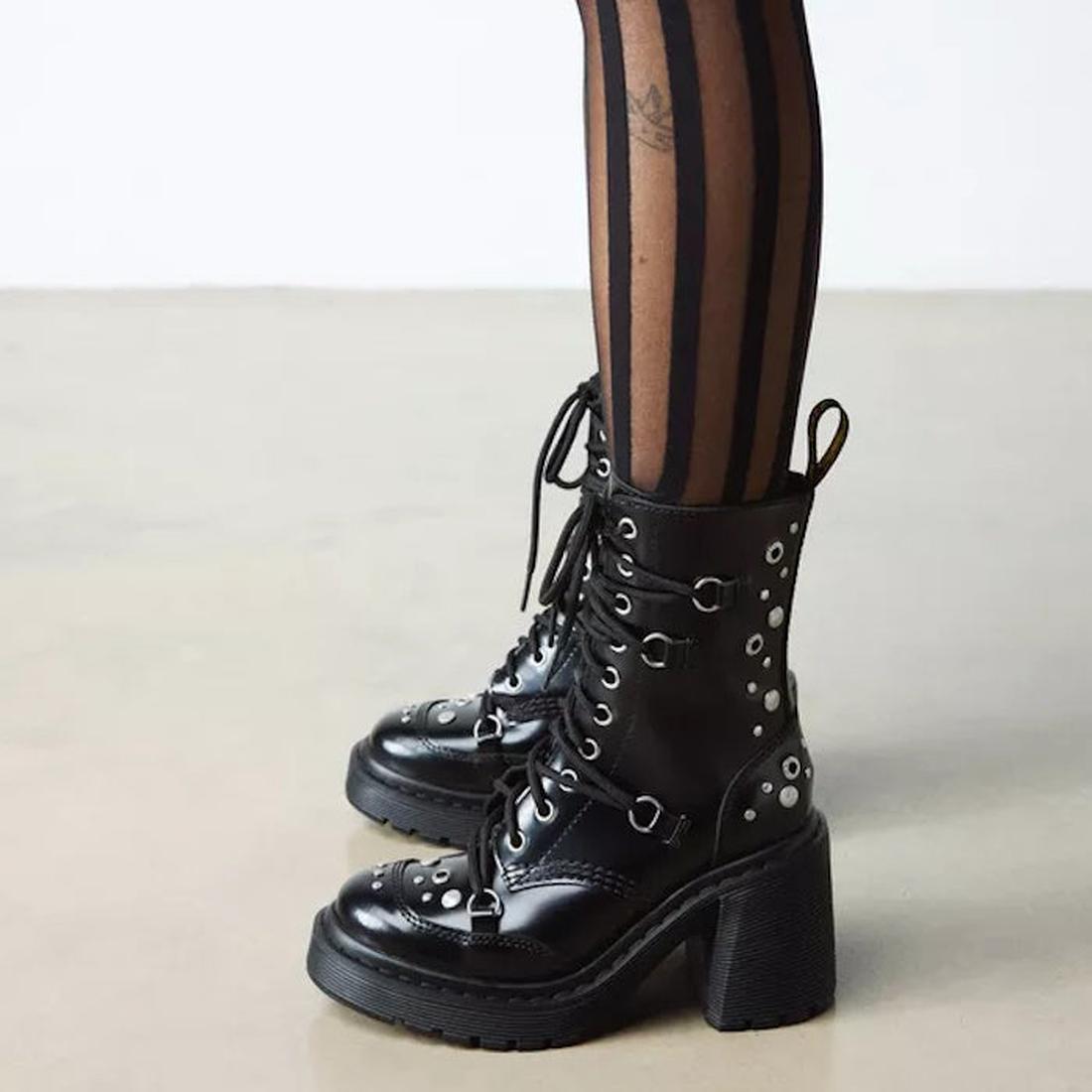 Black platform High Heeled Dr martens Chesney hardware studded and 10 eye lace up boot.Shoing the outer of the foot and leg with the bumper over the toe and dr martens heel loop boots with eyelets worn with striped tights on a neutral background
.,1906657