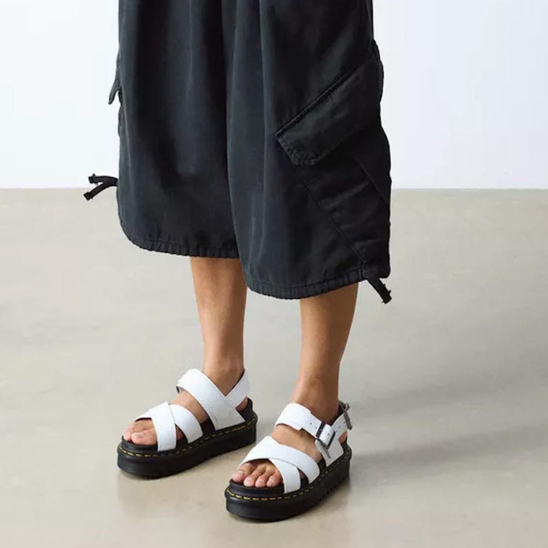 A person in cropped black pants wears the Voss II Cross Strap Sandal White by Doc, with comfy thick black soles and easy Velcro straps.  ksnz, 190665404579, 190665404586, 190665404593, 190665404616, 190665404623, 190665404630