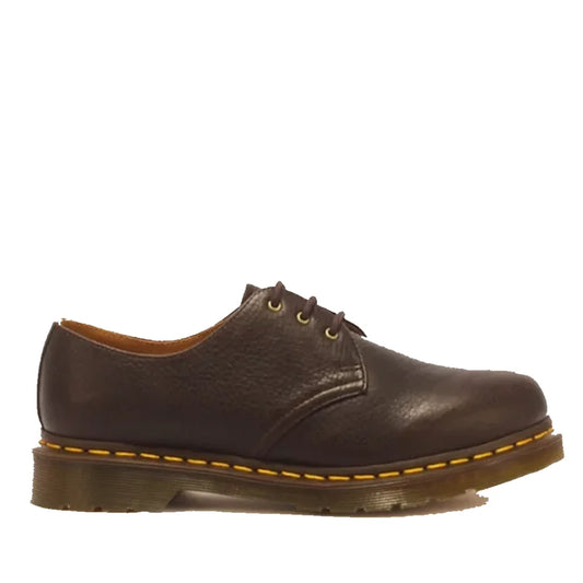 The Dr Martens 1461 Shoes in dark brown Ambassador leather are classic 3 eye lace up Oxfords, crafted from tumbled leather with a textured finish and accented by yellow stitching around the sole. Built with Goodyear welted construction for durability and 