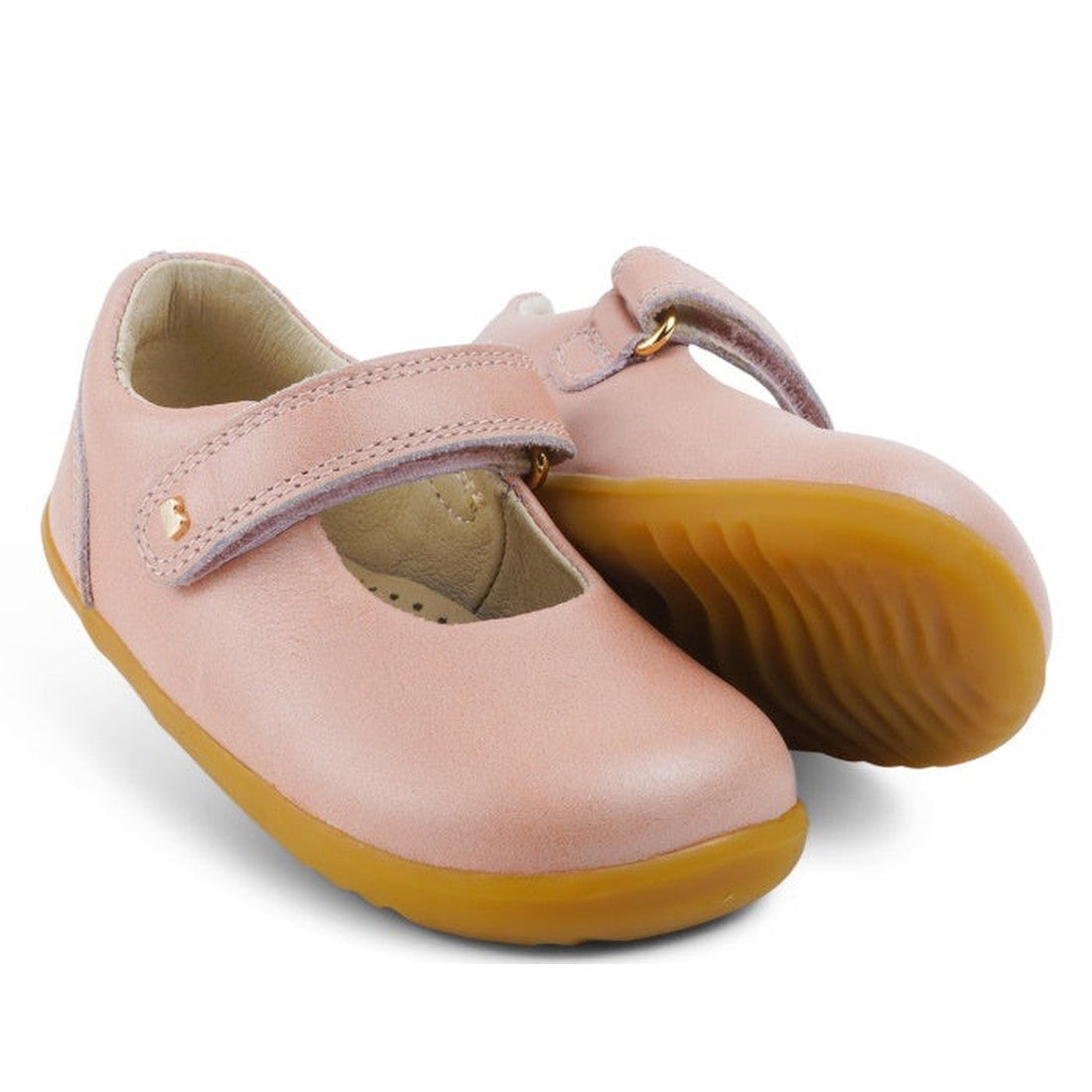 The Bobux Step Up Mary Jane Delight Dusk Pearl Pink 728426 is a pair of children's premium leather shoes with tan rubber soles and a hook-and-loop strap. One shoe stands upright, the other tilts to show the sole.