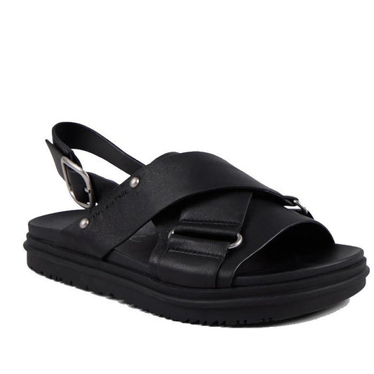 The Emu Faye Black Leather Sandal features a thick sole, cushioned footbed, crisscross leather straps with silver ring accents, adjustable slingback buckle, and an open toe for effortless style.