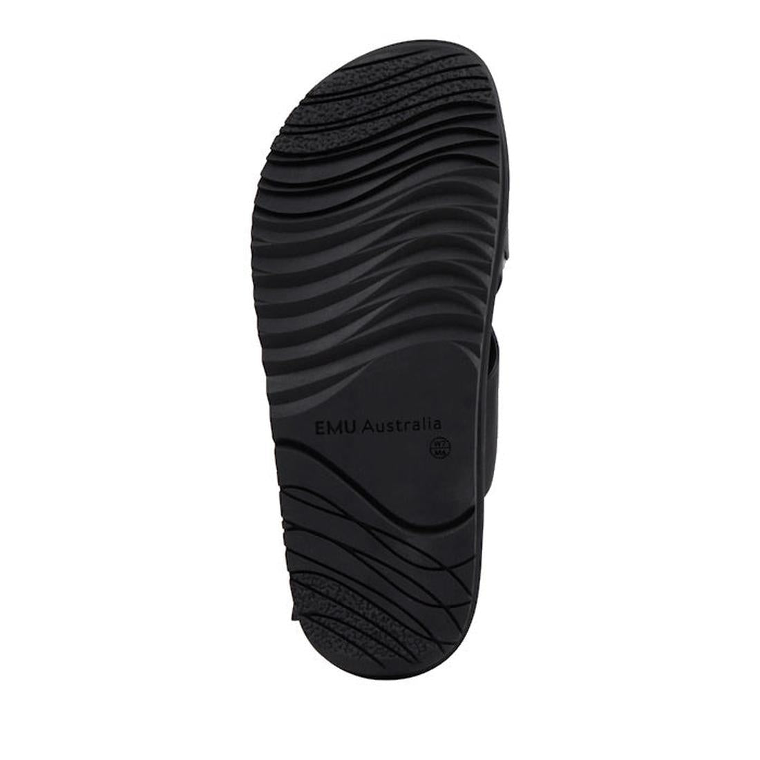The image shows the black rubber sole of the Emu Faye Black Leather Sandal w/Back Strap by EMU Australia, featuring a circular logo in the center and wavy, textured grooves for grip and traction., 9330071983119, 9330071983126, 9330071983133, 9330071983140