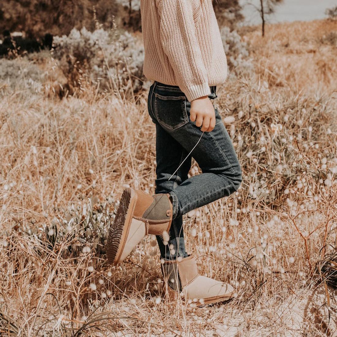 A chile wearingr the EMU Wallaby mini outdoors, featuring a patchwork design with chestnut, green, beige, and brown colors, made from merino wool and suede materials.,
9330071960721,
9330071960738,
9330071960745,
9330071960752,
9330071960769,
933007196077