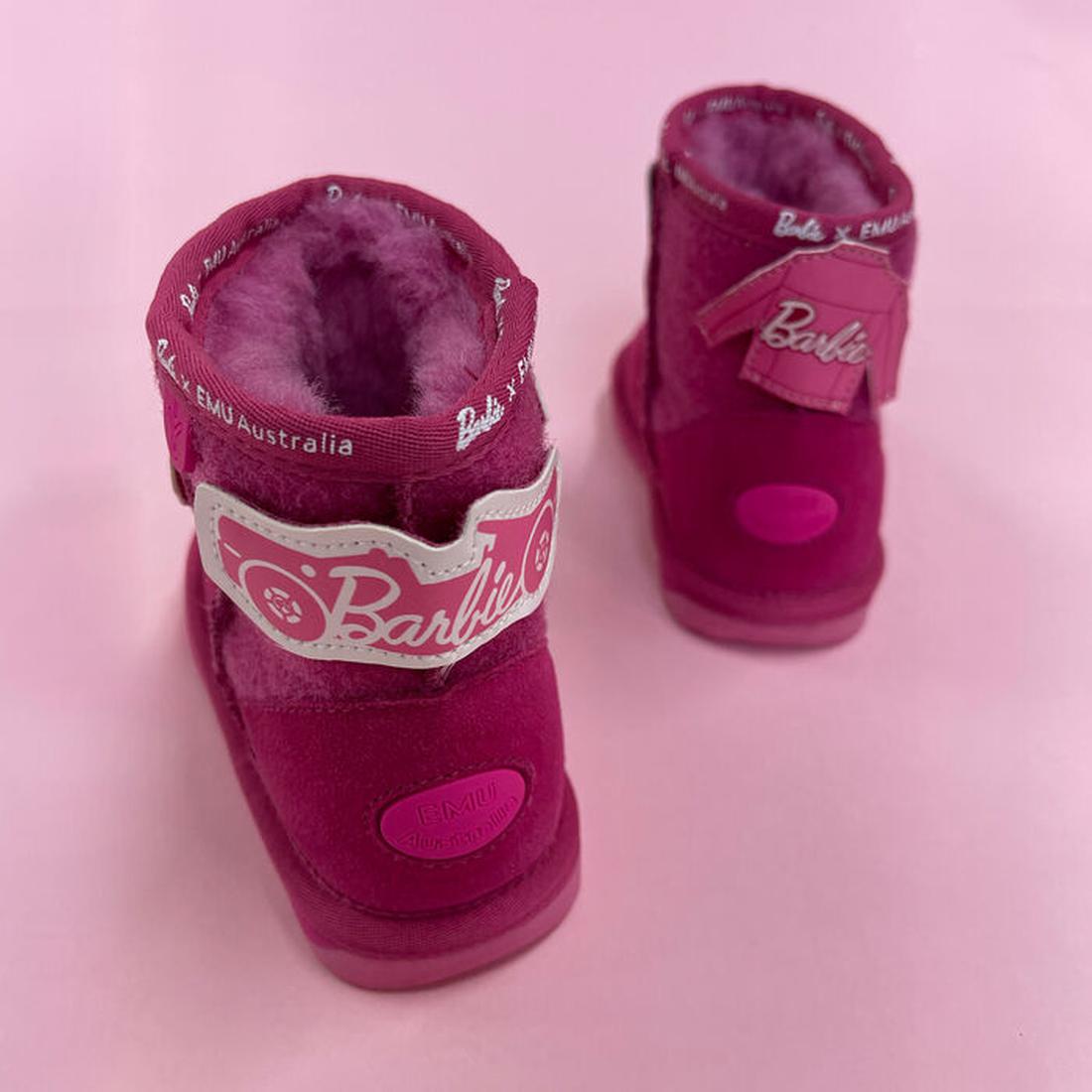 Two EMU Kids Wallaby Mini Play Barbie Pink boots with fluffy Australian Merino wool interiors, velcro straps, customisable patches, and EMU Australia branding sit on a pink surface. Designed for children., 9330071949733, 9330071949740, 9330071949757, 9330