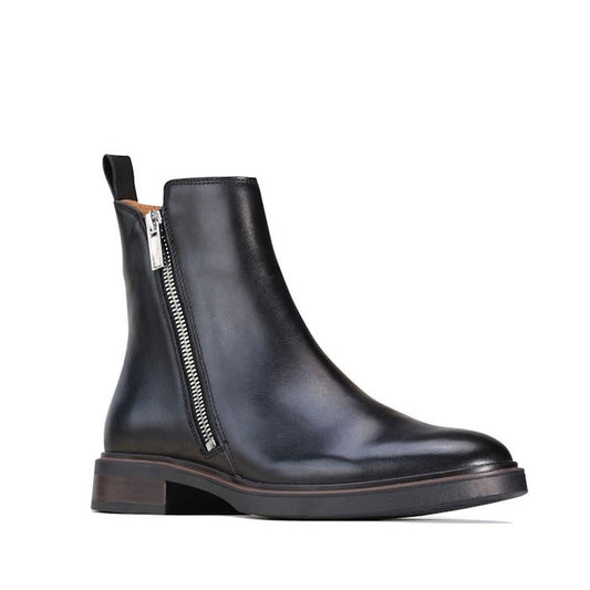 The right foot side and front view of the EOS Blaine black leather ankle boot with a double metal zip and an asymmetric cut, a fner looking tiie , featuring a low heel and a pull tab on the side.