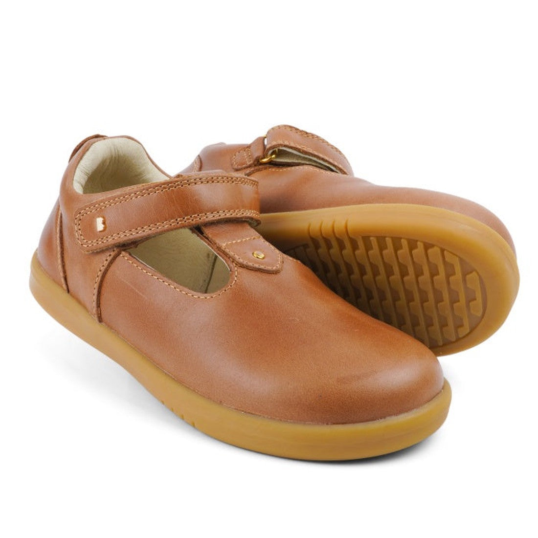 The Bobux Kids Plus KP Louise Caramel Tan T-Bar 833814Z are light brown leather children’s shoes with rubber soles and a hook-and-loop strap, shown in classic T-Bar style against a white background.