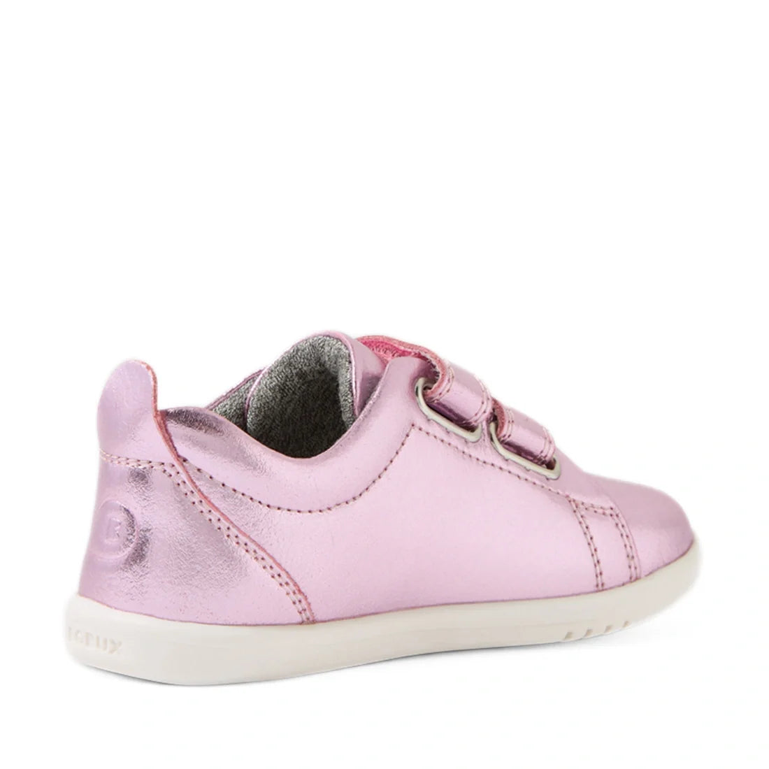 The Bobux Iwalk Toddlers Grass Court Pink Metallic Leather Trainer is a kids’ sneaker featuring two velcro straps, a bright white sole, and a stylish low-back heel. Shown from an angled rear view, this modern shoe stands out with its shiny metallic pink l