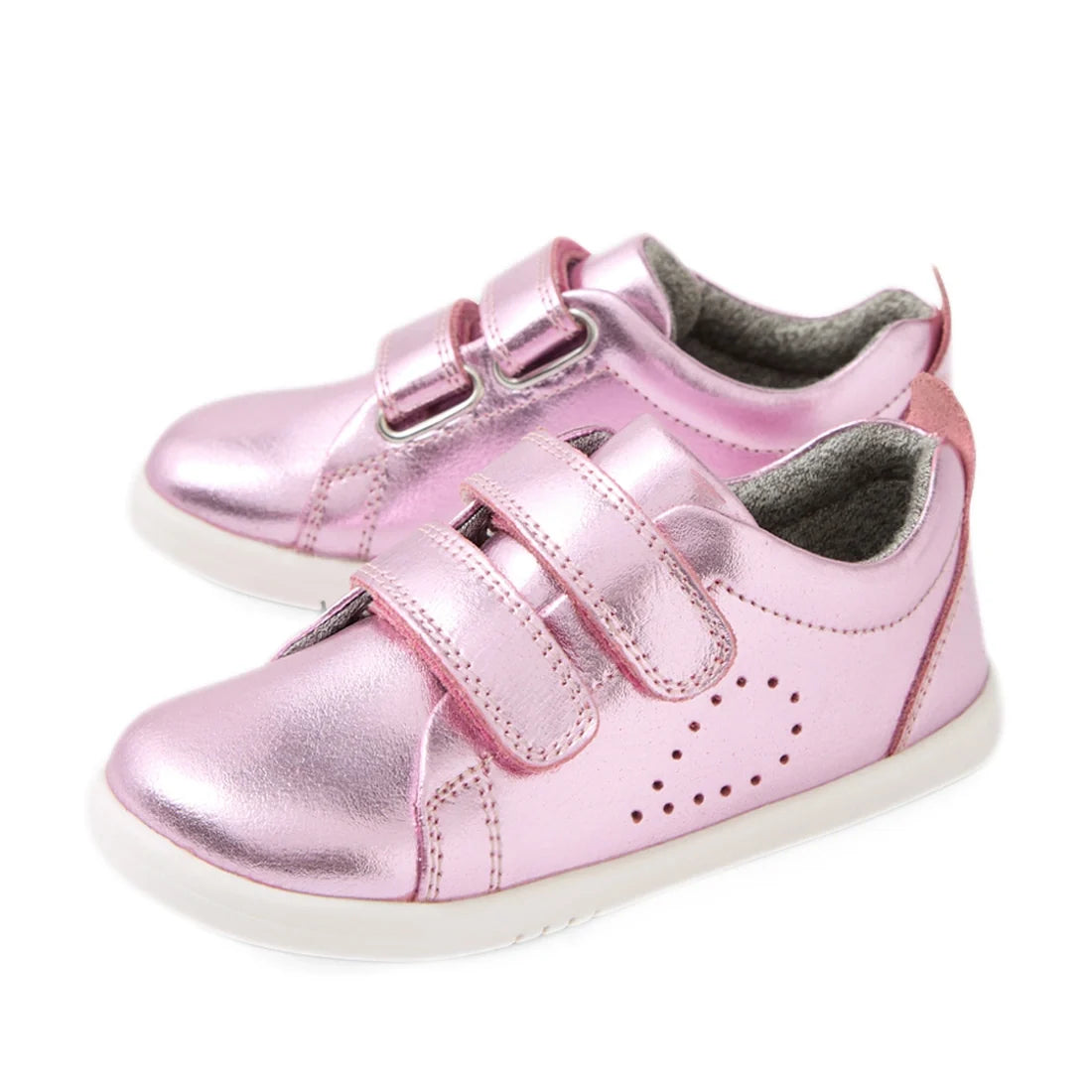 Shiny pink metallic toddler shoes with white soles, featuring two velcro straps and small perforated dots on the side for decoration, these Bobux Iwalk Toddlers Grass Court Pink Metallic Leather Trainers are perfect kids’ leather sneakers for everyday adv