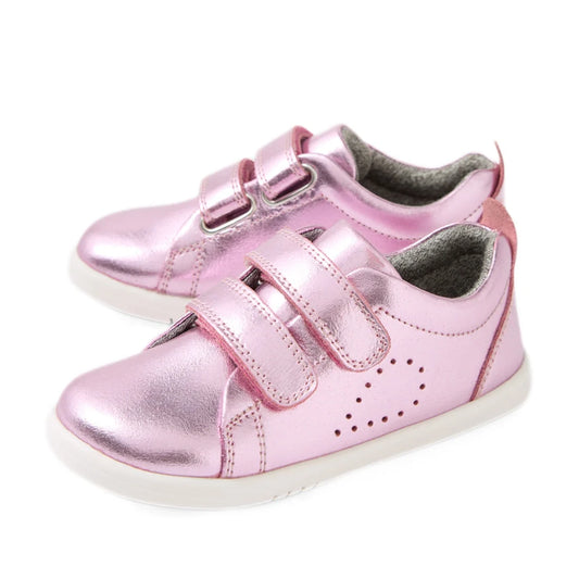 Shiny pink metallic toddler shoes with white soles, featuring two velcro straps and small perforated dots on the side for decoration, these Bobux Iwalk Toddlers Grass Court Pink Metallic Leather Trainers are perfect kids’ leather sneakers for everyday adv