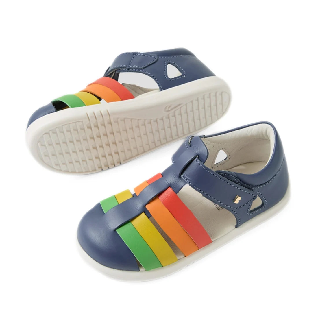 A pair of Bobux IWalk Tidal Sandal Multi Vintage Indigo Closed Toe Toddlers, featuring vintage indigo blue with white soles and multicolored straps in green, yellow, orange, and red across the top. Crafted from water-friendly leather, these closed-toe tod