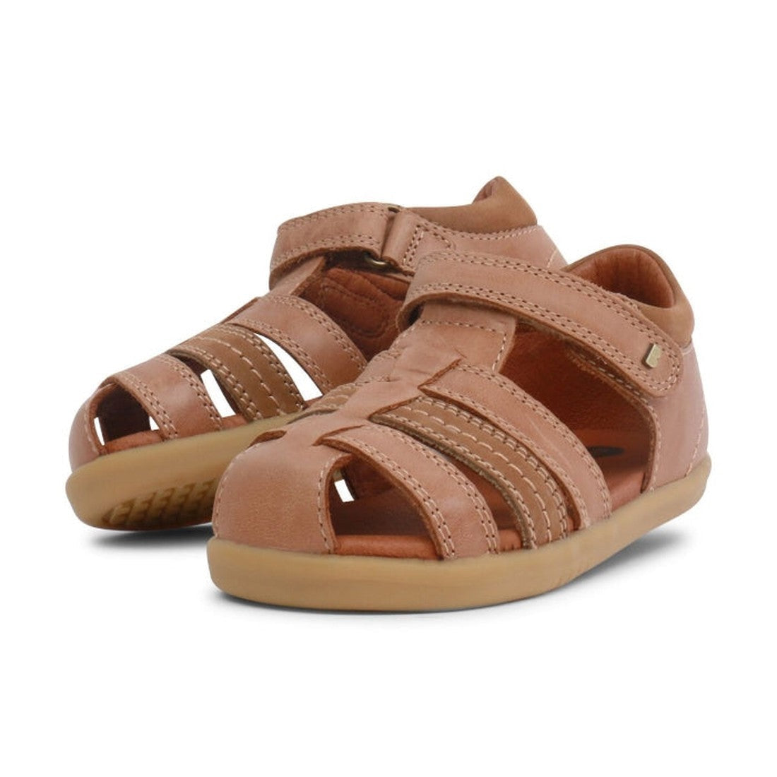 A pair of caramel tan bobux i walk sandals roam. angled to show the inside and outside of the feet and a small portion of the sole. Shows the toe covered with woven straps to allow are to circulate while still having protection. The heel supported and vel