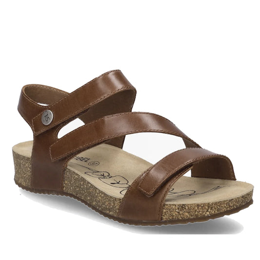 The Josef Seibel Tonga 25 Womens Leather Comfort Sandal in Camel Tan features a leather design with two straps across the foot, a back strap adorned with a metal button, and a cork sole with a cushioned footbed. The sandal is shown angled slightly to the 