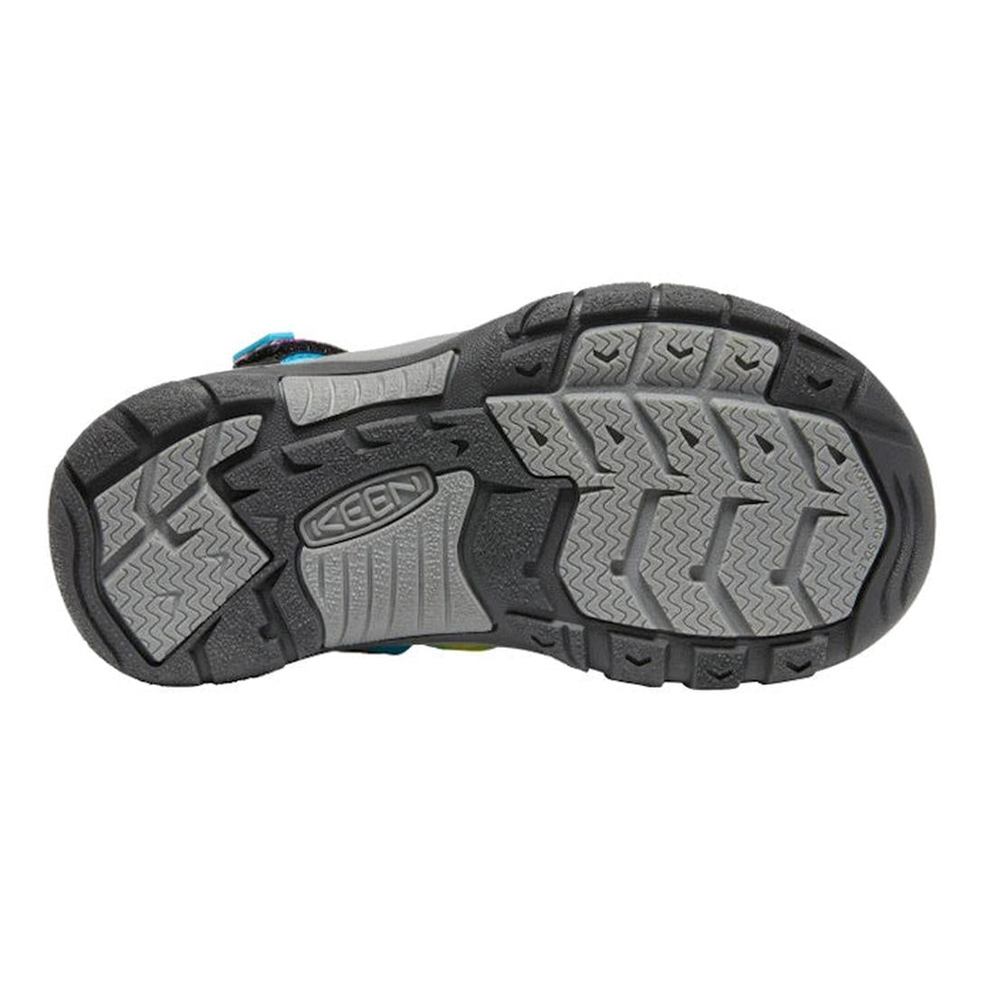 The image displays the rubber sole of the KEEN Kids Newport H2 Youths Sandal in Rainbow Tie Dye, with gray and black textured patterns for enhanced traction and the KEEN logo embossed at the center. This water-friendly closed-toe sandal is designed to pro