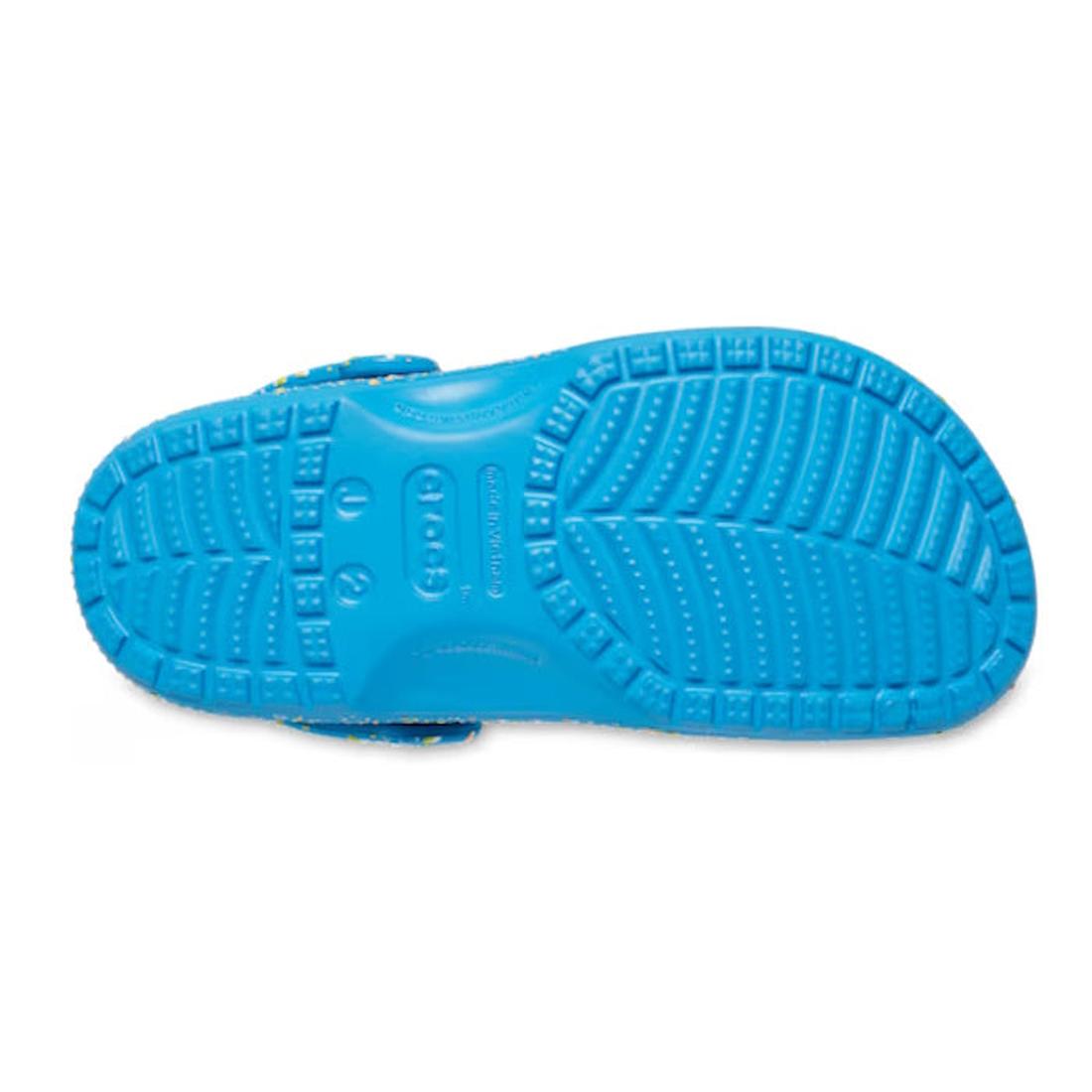 The Crocs Kids - Youths Classic Clog K Paint Splatter Print Blue Multi is shown from the bottom, highlighting its vibrant blue tread with multiple grooves and textures for added grip., 198445210136, 198445210143, 198445210150, 198445210167, 198445210174, 