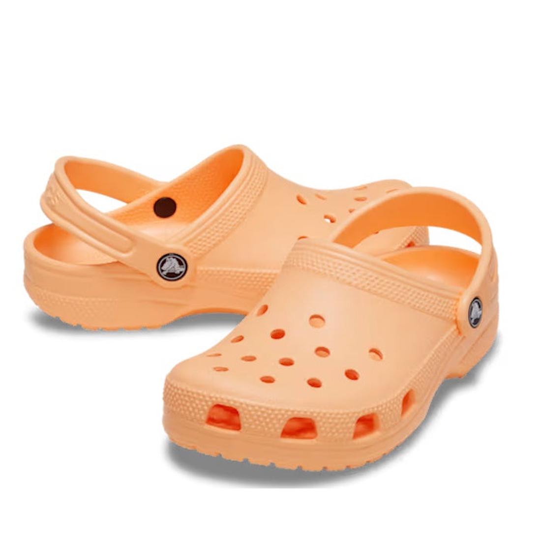 A pair of Crocs Kids - Classic Clog Sunstone Soft Orange in junior youth sizes, featuring ventilation holes and adjustable heel straps, water-friendly and ideal for daily wear, displayed on a plain white background.