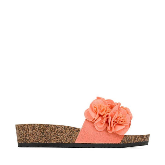 The Los Cabos Corsage Tango Peach Flower Women's Slides feature a cork wedge heel and a wide suede strap with layered fabric flowers on top, shown from the side against a white background.