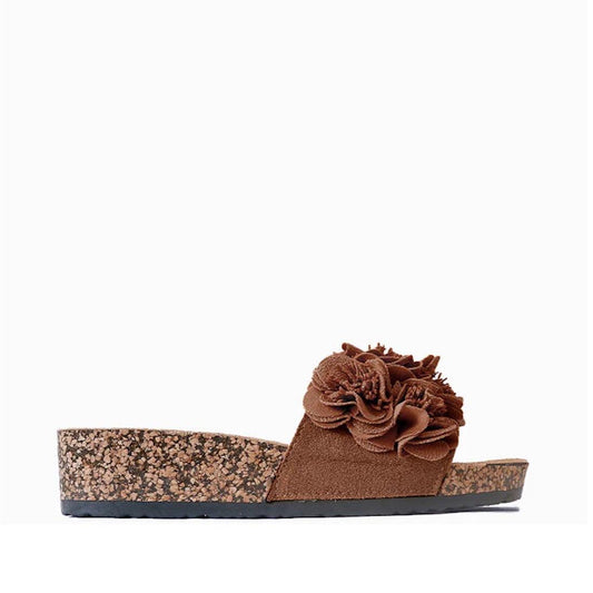 The Los Cabos Corsage Truffle Brown Flower Women's Slides feature a cork wedge heel and wide suede strap with layered fabric flowers, making them the perfect summer shoe. Displayed against a plain white background.