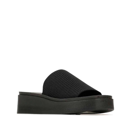 The Los Cabos Pass Women's Wedge Heeled Slide Sandal in black features a thick, ribbed fabric strap, padded insole for comfort, and a chunky flatform sole, displayed against a plain white background.