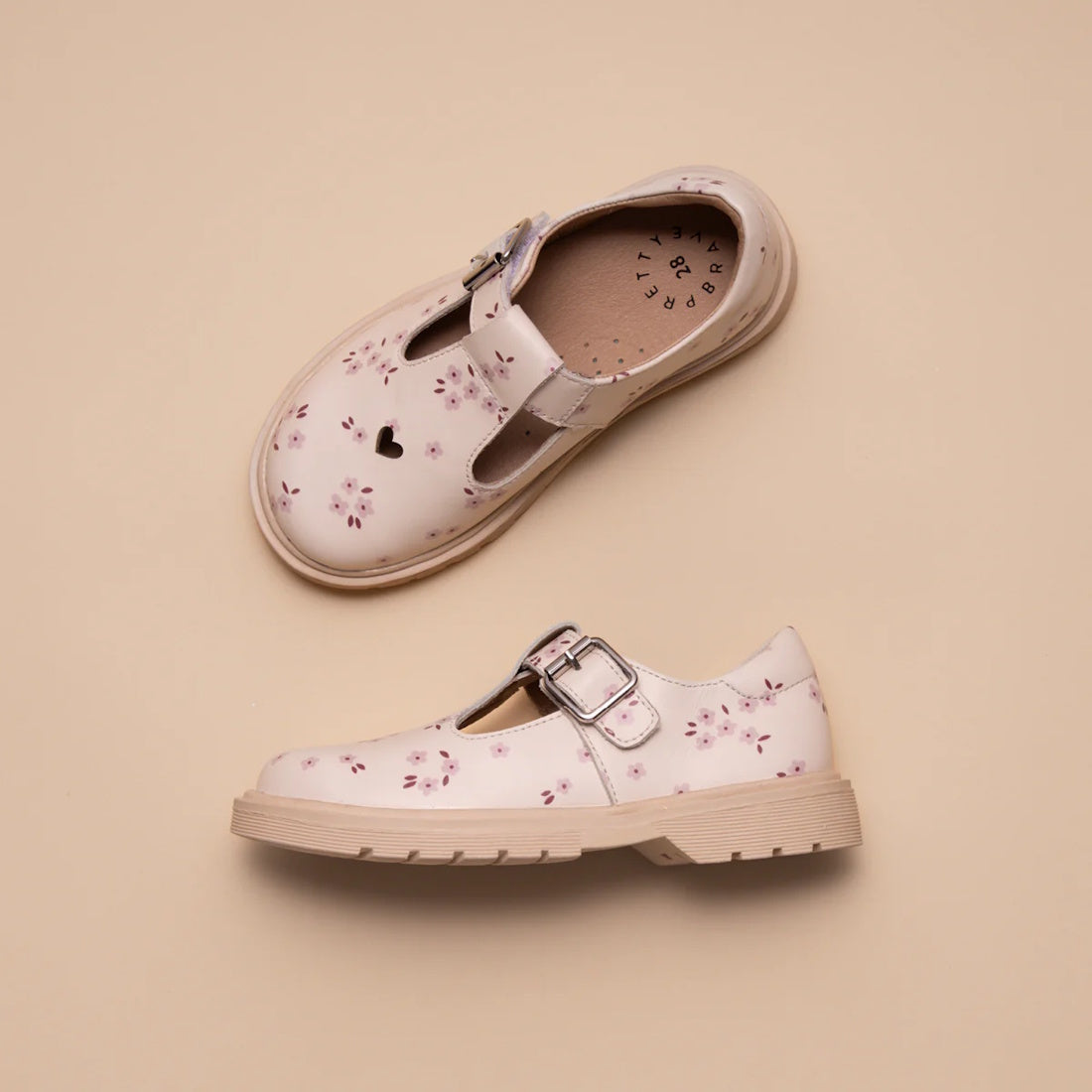 Two Pretty Brave Girls Maddison Winter Bloom Pink Leather Mary Jane T Bar shoes are displayed on a beige background. One shoe, shown from above, features a heart-shaped cutout near the toe and floral patterns with silver buckles., 9420075362840, 942007536