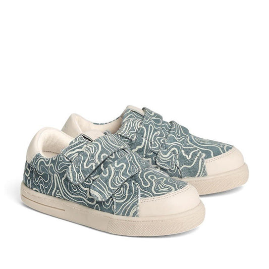 The Pretty Brave Otto Organic Canvas Trainer With Leather Toe Buffer Blue Ripple features a blue and white swirling pattern, white soles and accents, Velcro straps, rounded toe, and soft bamboo cotton lining for comfort.