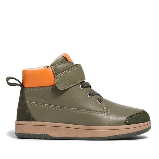 The Pretty Brave Hi Top Boot Corey Olive is a kids’ olive green leather high-top with a tan sole, orange ankle collar, hook-and-loop strap, laces, and heel pull tab, shown in profile facing right on a white background.