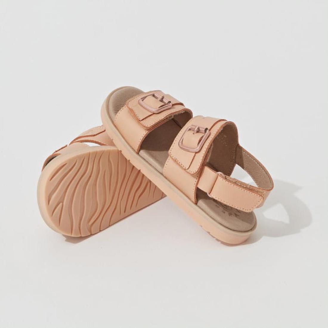 A pair of Pretty Brave Alex Leather Sandals in coral, sizes 29-33, with thick soles, a supportive back strap, two adjustable velcro straps on top, and a comfy leather footbed. One sandal stands while the other leans against it on a white background. CLEAR