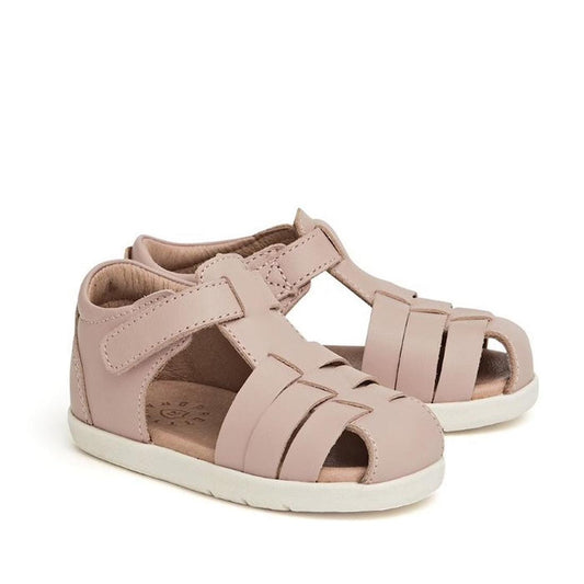 The Pretty Braver Billie First Walker Sandal Closed Back Blush is a light pink children’s sandal featuring closed toes, woven straps, open sides, adjustable Velcro ankle straps, white soles, and a comfortable, breathable design.