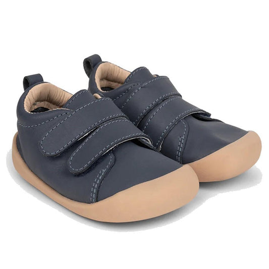 The Pretty Brave First Walker Toto Leather Trainer in Indigo Blue features flexible navy leather, beige rubber soles, and two Velcro straps per shoe, perfect for toddlers learning to walk. Displayed on a white background., 9420075366275, 9420075366268, 94