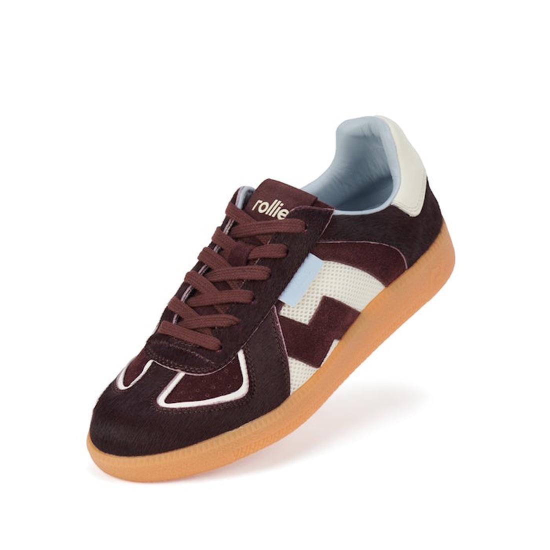 The Rollie Womens Pace Dark Cherry Bone Suede Sneaker features a brown and white suede upper, light blue accents, brown laces, a tan rubber sole, and the rollie brand name on the tongue, shown against a white background.