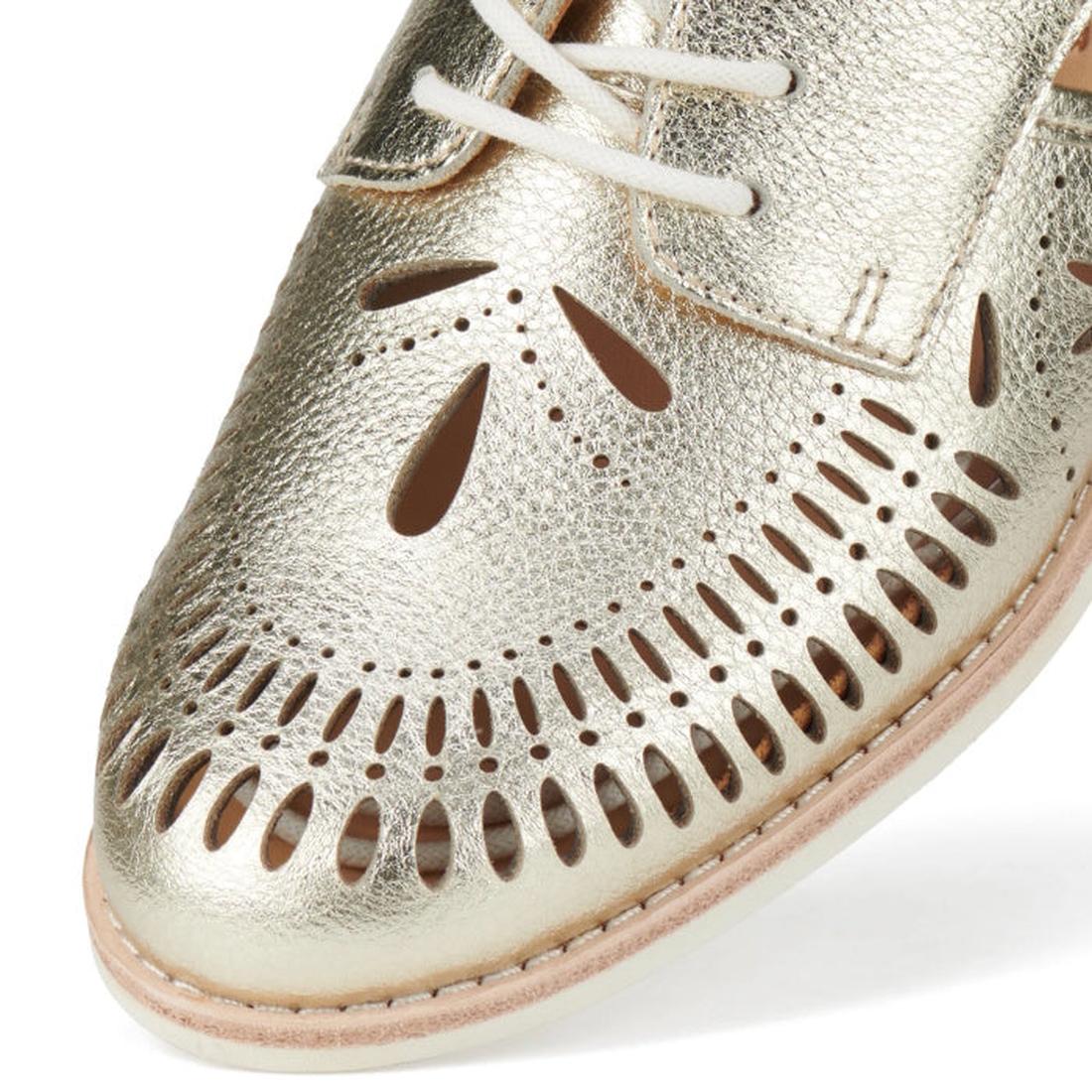 Close-up of the toe of the Rollie Womens Sidecut Boho Punch Gold Leather Shoe, featuring white laces, intricate cutout patterns revealing light brown underlays, and a memory foam footbed for all-day comfort in Boho style., 9381760798811, 9381760798828, 93