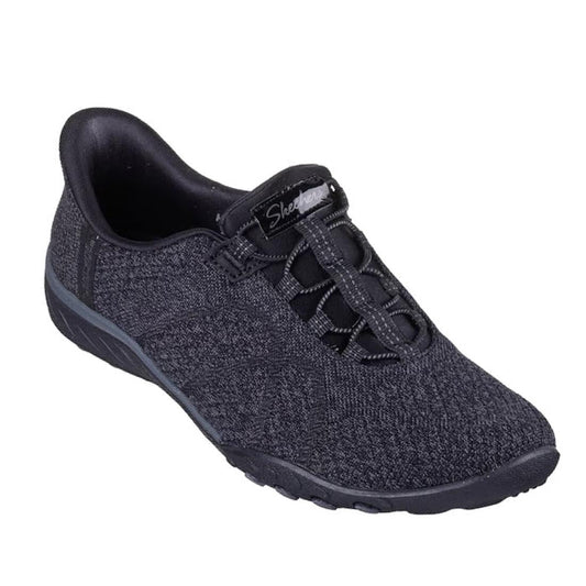 The Skechers Breathe Easy Knitty Waves SLIP IN Black is a hands-free athletic shoe featuring a textured fabric upper, elastic bungee laces, Air-Cooled Memory Foam comfort, and a black cushioned sole.