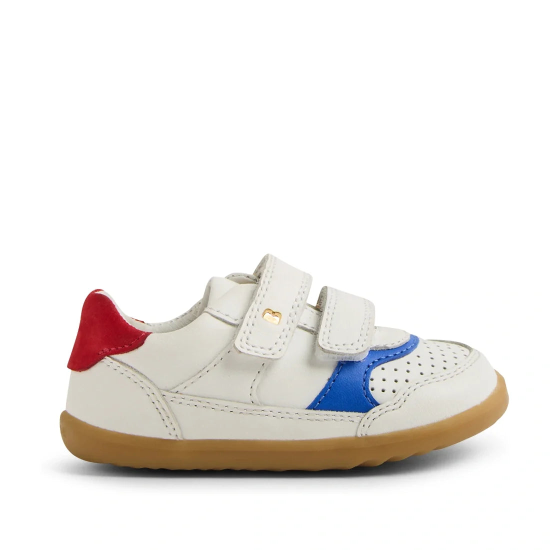 The Bobux SU Step Up Hunter Leather Toddlers Sneaker in White Salsa features a small white leather design for kids, with red, blue, and tan accents, two hook-and-loop straps, a perforated toe, and a tan rubber sole. The sneaker is displayed from the side 