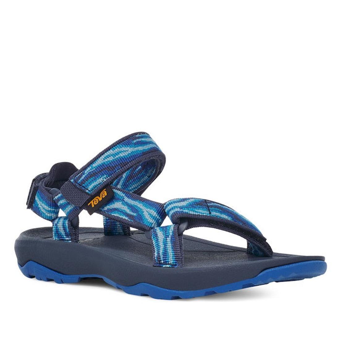 A single Teva Kids K Hurricane XLT2 Wave Mood Indigo sandal with adjustable recycled webbing straps in a blue and white pattern, black sole, and Velcro fastening.