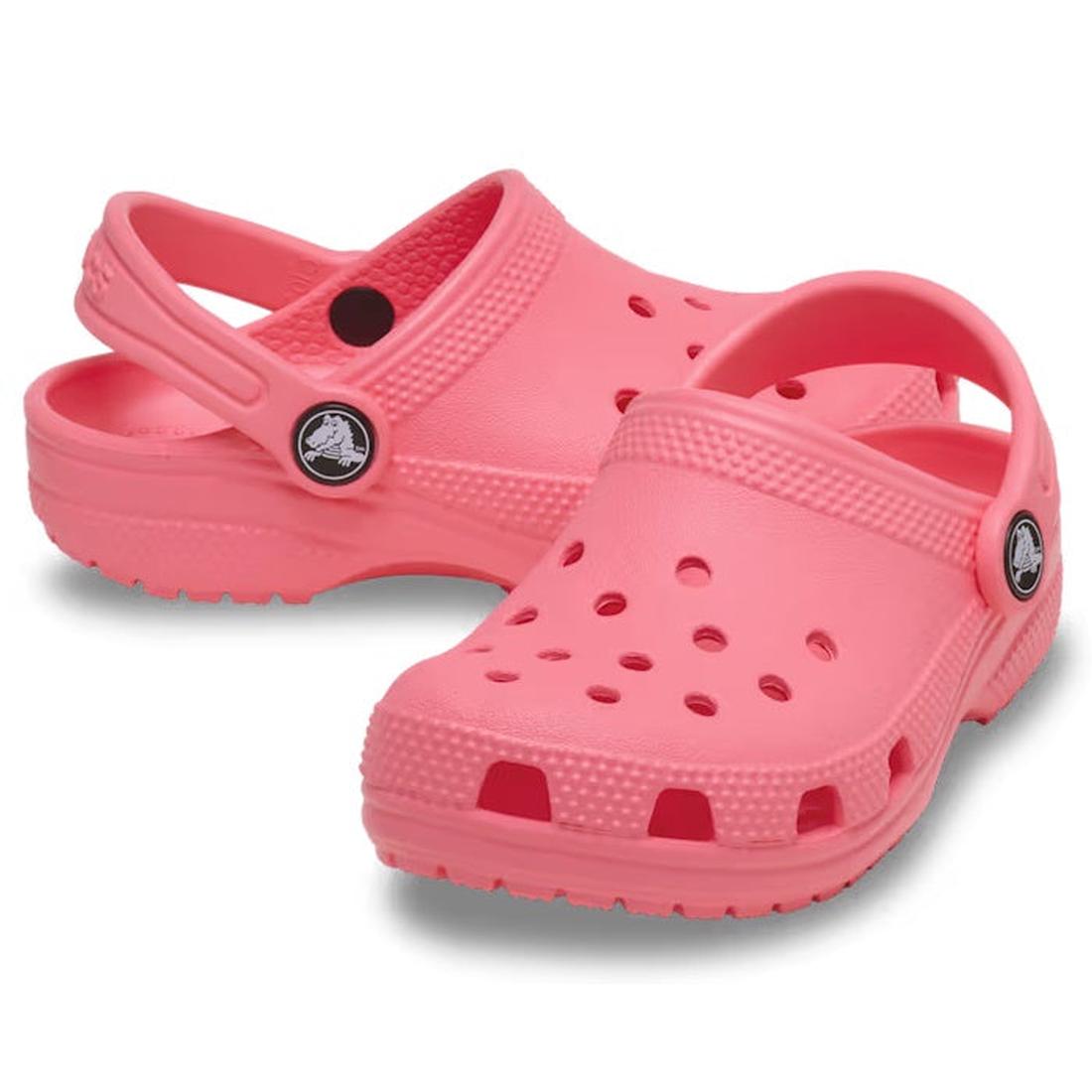 A pair of Crocs Kids Toddlers Classic Clog in Guava Pink, featuring ventilation holes and adjustable heel straps, is shown against a white background.