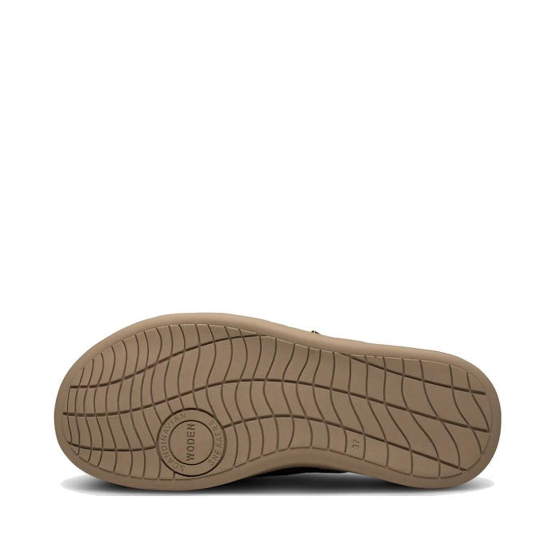 The image shows the bottom of the Woden Womens Vega Clog Suede Mule in Silver Mink - Beige, featuring a tan sole with a textured, wavy tread and a circular WODEN logo near the heel against a plain white background., 42722, 5713326514100, 5713326514117, 57