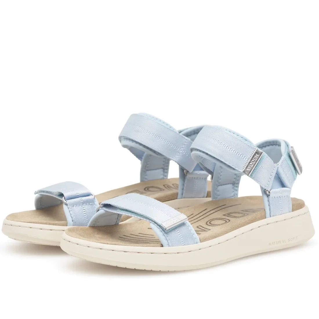 The Woden Line Women's 3 Strap Sandal in Moonstone Light Blue features adjustable Velcro straps and beige cushioned soles, crafted from sustainable materials for all-day comfort. The sandals are displayed at a slight angle on a white background.