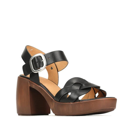 The EOS Spirited Womens Black Leather Heeled Platform Sandal features woven front straps, a thick wooden block heel and platform, plus an ankle strap with a large silver buckle.