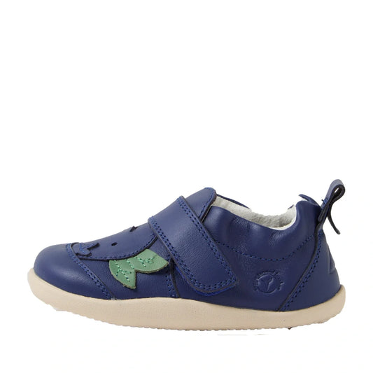 The Bobux XP Explorer Little Sprouts Blueberry Dash First Walker Blue is a blue toddler shoe with a velcro strap, beige flexible sole, and a small green leaf detail on the side, designed as an ideal pre-walker shoe for young children.